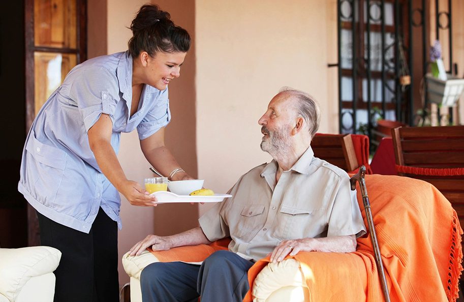 A woman serving food to an older man.