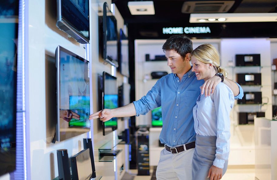 A man and woman looking at televisions in a store.