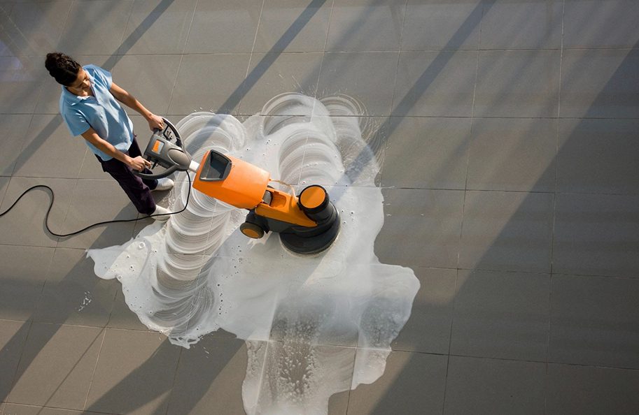 A person is using an electric floor scrubber.