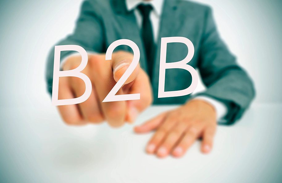 A man pointing to the word b 2 b written in white marker.