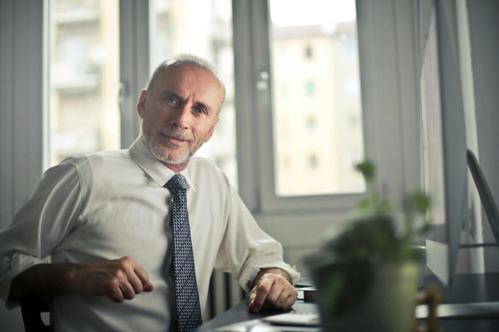 A man sitting at a table with his hands on the chair.